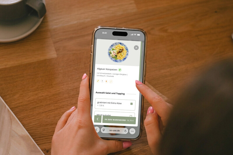 Nutzer bestellt Allg&auml;uer K&auml;sspatzen &uuml;ber eine Smartphone-App in einem Restaurant