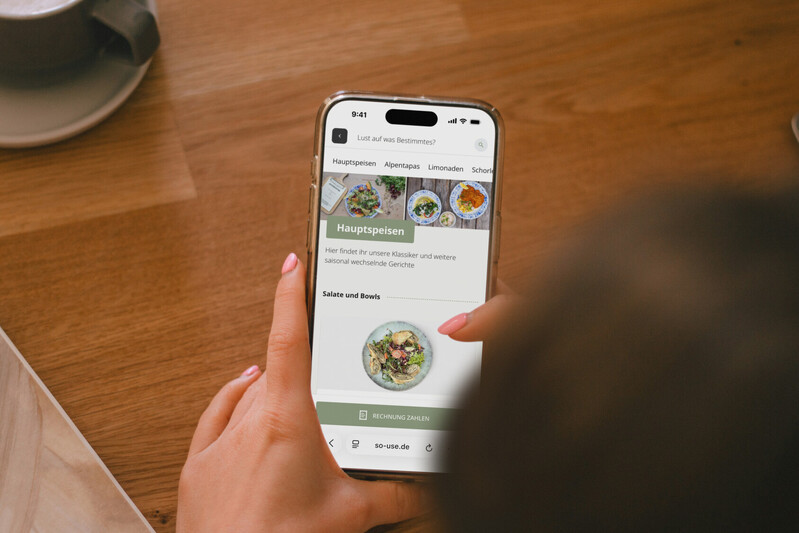 Person bedient das digitale Men&uuml; auf dem Smartphone in einem Restaurant